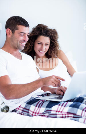 Happy couple using laptop on bed Stock Photo