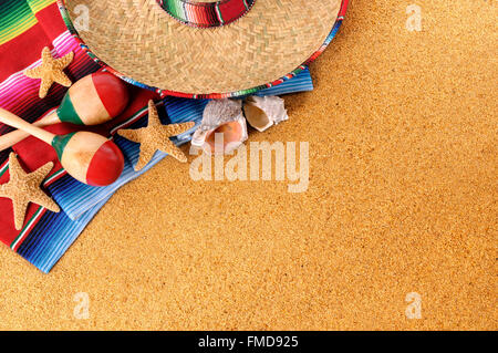 Mexican beach background with sombrero straw hat, traditional serape blanket, starfish, seashells and maracas.  Space for copy. Stock Photo