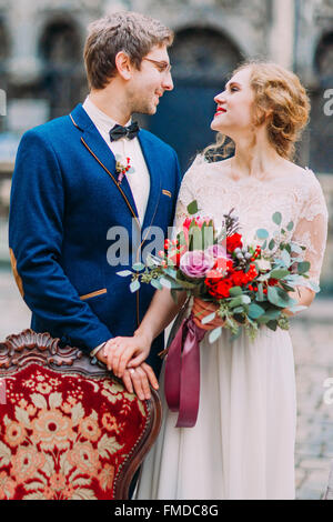 Happy groom and bride lovingly look at each other and smile Stock Photo