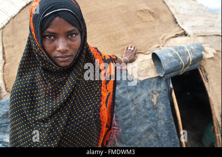 Young muslim woman belonging to the Afar tribe. Behind her, the hut where she is living is visible ( Ethiopia) Stock Photo