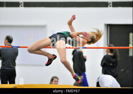 A high school athlete attempting to clear the high jump bar at an indoor meet. USA. Stock Photo