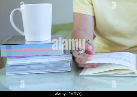 Women study hand holding a pen with a coffee mug on side Stock Photo