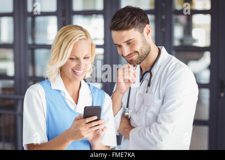 Smiling doctors using mobile phone Stock Photo
