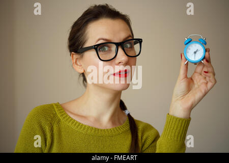 Little blue alarm clock in the hands of young woman, concept of saving time Stock Photo