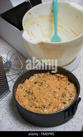 Baking a carrot cake. Raw mixture in a tin and the empty bowl with spatula Stock Photo