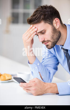 Tensed businessman using mobile phone by table Stock Photo