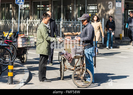 Street vendor selling potatoes to a customer in Beijing, China. Stock Photo