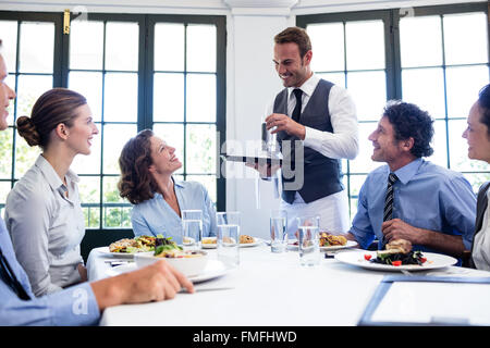 Waiter serving water to business people Stock Photo