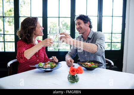 Happy middle-aged couple toasting champagne flutes while having lunch Stock Photo