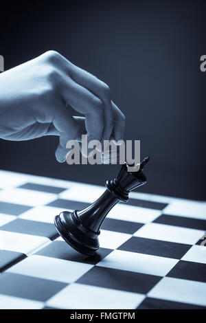 Close-up image of a hand moving a chess piece and defeating the challenger. Stock Photo