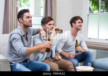 Young male friends drinking beer while watching TV Stock Photo