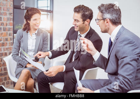 Happy business people holding documents while sitting on chairs Stock Photo