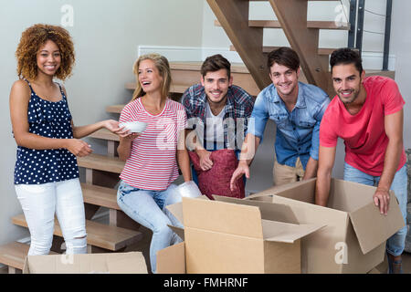 Happy young friends by cartons in new house Stock Photo