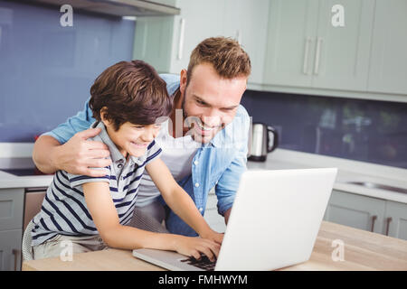 Smiling father and son working on laptop Stock Photo