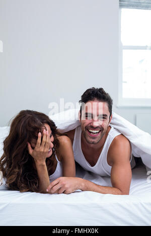 Smiling couple lying under blanket Stock Photo