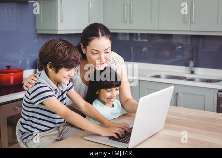 Smiling mother and children working on laptop Stock Photo