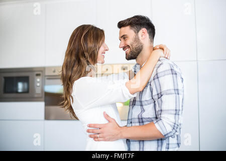 Couple embracing by in kitchen Stock Photo