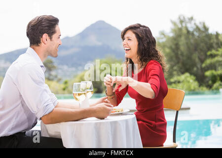 Cheerful couple sitting by swimming pool Stock Photo