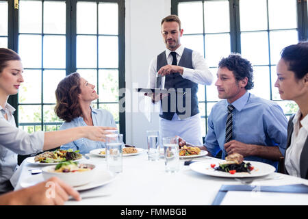 Waiter serving water to business people Stock Photo