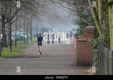 People enjoyed a bright but misty day on and around the Thames in London. The Thames Walk in Battersea Park is popular with joggers Stock Photo