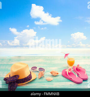 Fashion accessories summer flip flops, hat, glasses on bright turquoise blue board on the beach Stock Photo