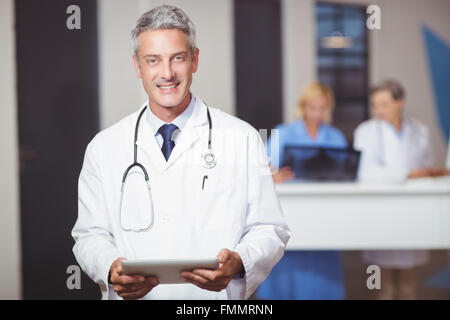 Portrait of smiling senior doctor holding digital tablet Stock Photo
