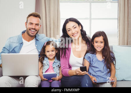 Happy family using modern technologies while sitting on sofa Stock Photo