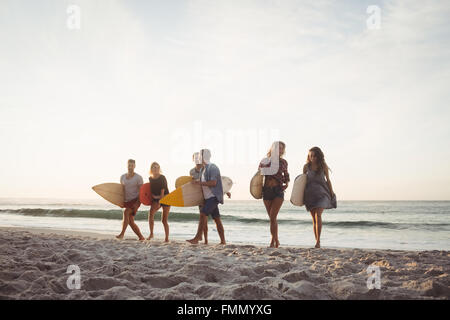 Happy friends walking with surfboards