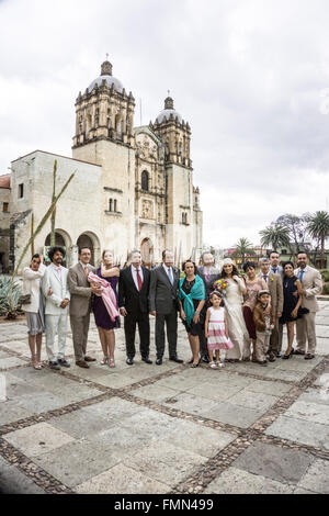 happy bride & groom pose with both families, bride's on right, groom's on left with all their youngest members on church Plaza Stock Photo