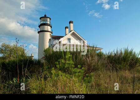 Low angle sun illuminates Highland lighthouse which is surrounded by shrubbery on Cape Cod. Stock Photo