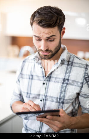 Confused young man using digital tablet in kitchen Stock Photo