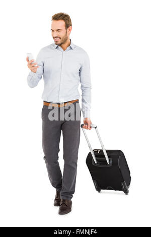 Young man holding trolley bag and using mobile phone Stock Photo