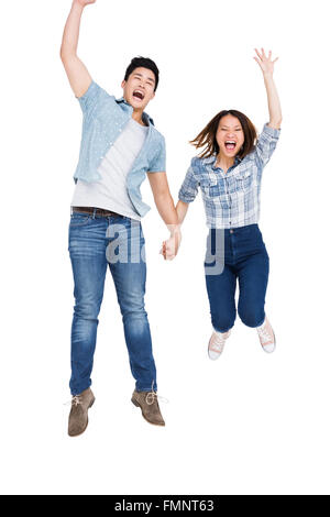 Excited young couple holding hands and jumping Stock Photo