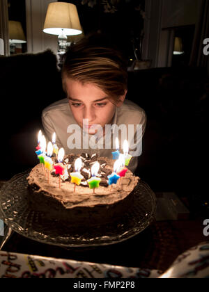 A boy blows out his birthday cake candles Stock Photo