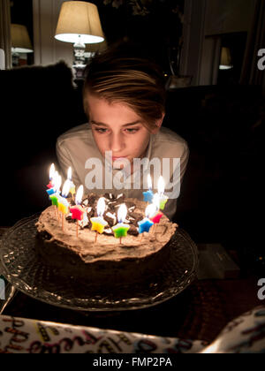 A boy blows out his birthday cake candles Stock Photo
