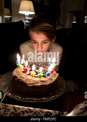 A boy blows out his birthday cake candles Stock Photo