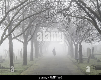 A ghostly figure walks in the fog in a graveyard Stock Photo