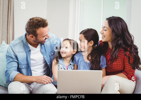 Family smiling and using laptop on sofa Stock Photo