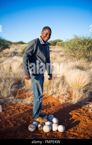 Local man standing on ostrich eggs, Kalahari Anib Lodge, Mariental, Namibia Stock Photo