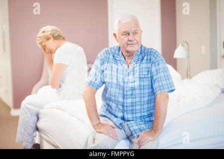 Tensed senior couple sitting on bed Stock Photo