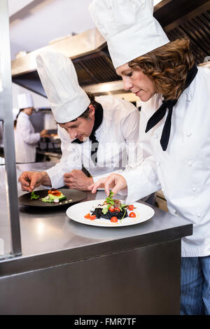 Two chefs garnishing meal on counter Stock Photo
