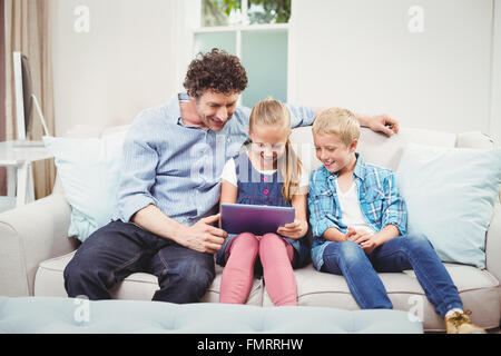 Father with children using digital tablet on sofa Stock Photo