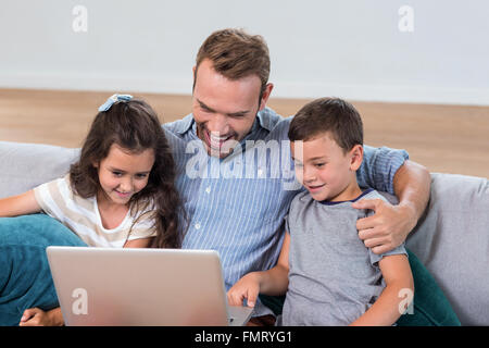 Father sitting with son and daughter and using laptop Stock Photo
