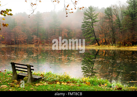 Fall sunrise landscape on peaceful lake with park bench at Chenango Valley State Park in Chenango Forks, Broome County upstate New York, USA. Stock Photo