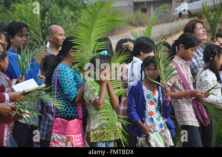 Attendand cover their face from the sunlight with palm leaves during Palm Sunday Mass at St. Josepf Church in Batam, Indonesia,  Stock Photo