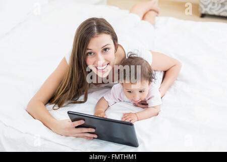 Mother holding tablet PC with baby at home Stock Photo