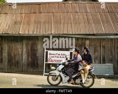 Luang Prabang, Luang Prabang, Laos. 13th Mar, 2016. Lao people ride a motorcycle past a home for sale in Luang Prabang. The for sale sign being in English indicates who the property is being marketed to. Luang Prabang was named a UNESCO World Heritage Site in 1995. The move saved the city's colonial architecture but the explosion of mass tourism has taken a toll on the city's soul. According to one recent study, a small plot of land that sold for $8,000 three years ago now goes for $120,000. Many longtime residents are selling their homes and moving to small developments around the city. Stock Photo