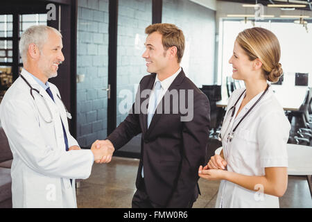 Two confident doctors shaking hands with each other Stock Photo