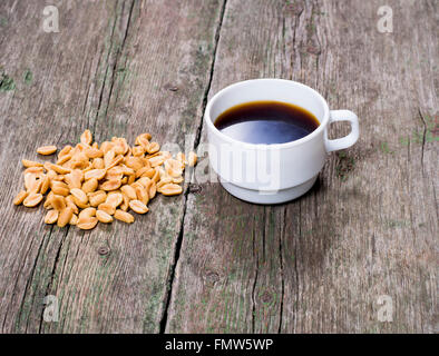 the scattered peanut and cup of coffee on a wooden table Stock Photo