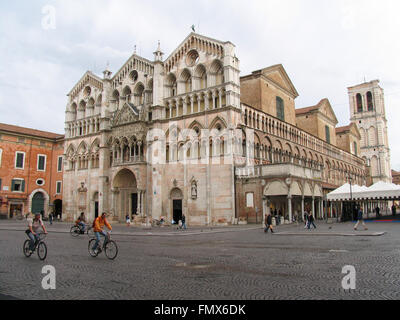 Cyclists  riding in the Piazza della Cattedrale in front of the Ferrara Cathedral. Stock Photo